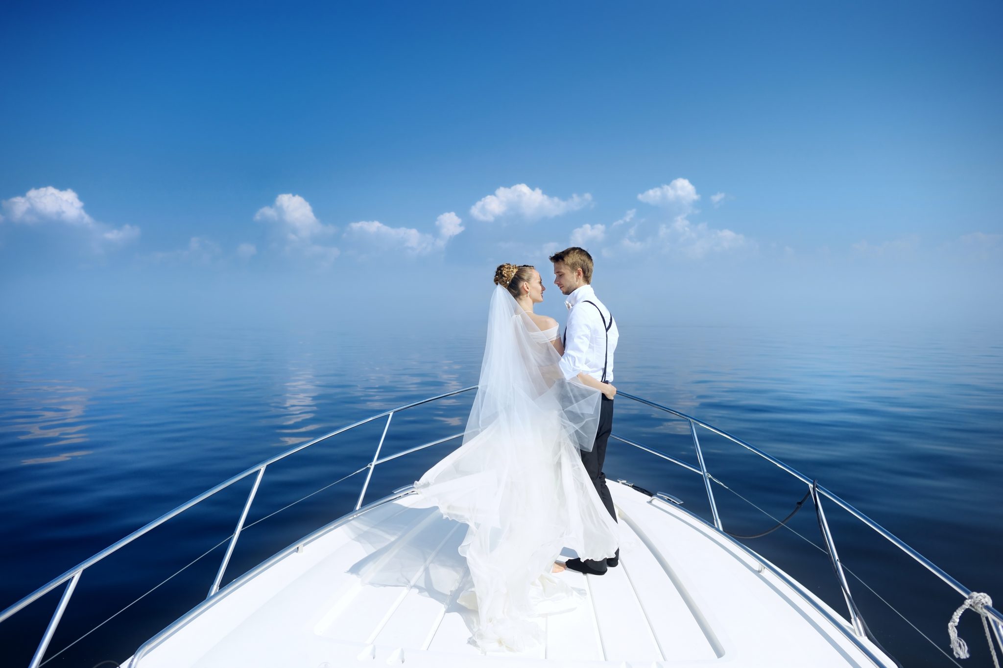 Happy bride and groom hugging on the bow of a yacht wedding