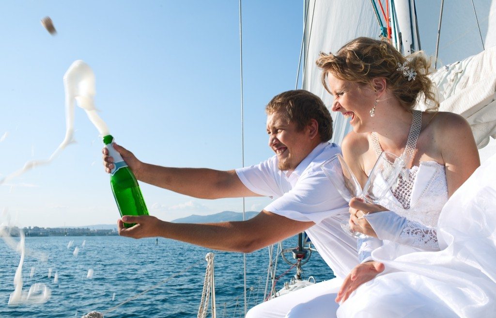 Bride and groom popping champagne cork on the deck of yacht