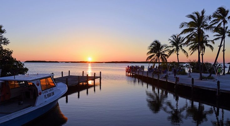 Sultry Florida sunset on the water w boat, dock and palm trees