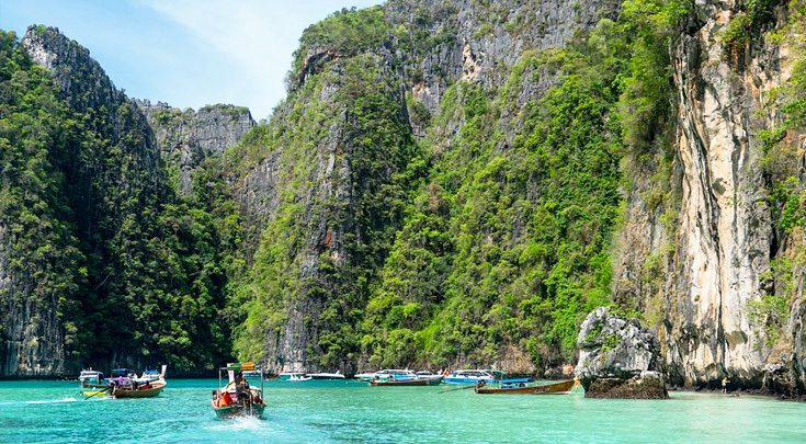 Thailand Asia boats paddling through water surrounded by cliffs