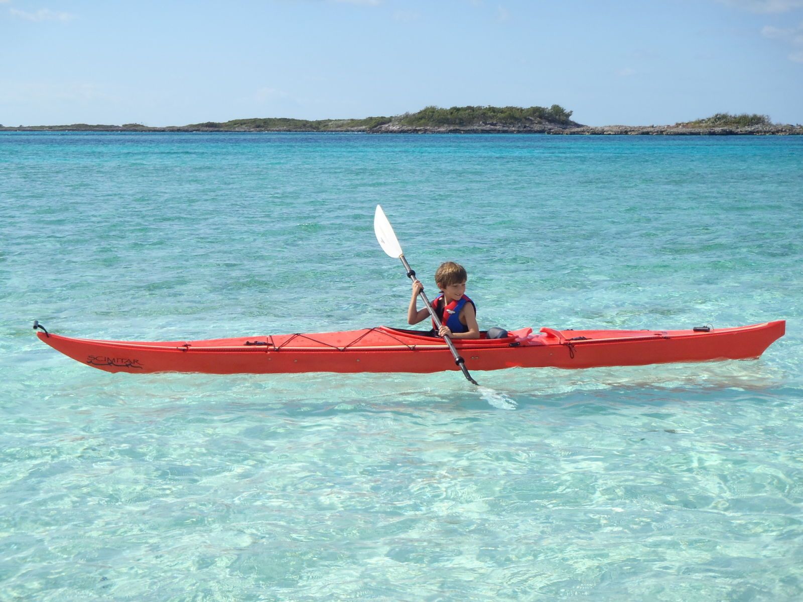 Boy paddling red kayak M/Y ZOOM ZOOM ZOOM