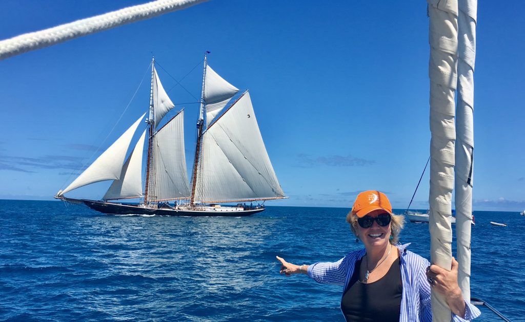 Carol Kent sailing on the S/Y EMILY MORGAN at the 2017 America's Cup in Bermuda pointing at the 141' S/Y COLUMBIA