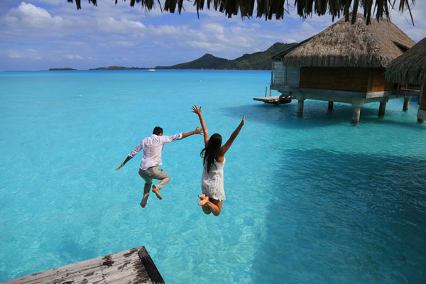 Happiness jump of young couple into the water near bungalows at Bora Bora, French Polynesia
