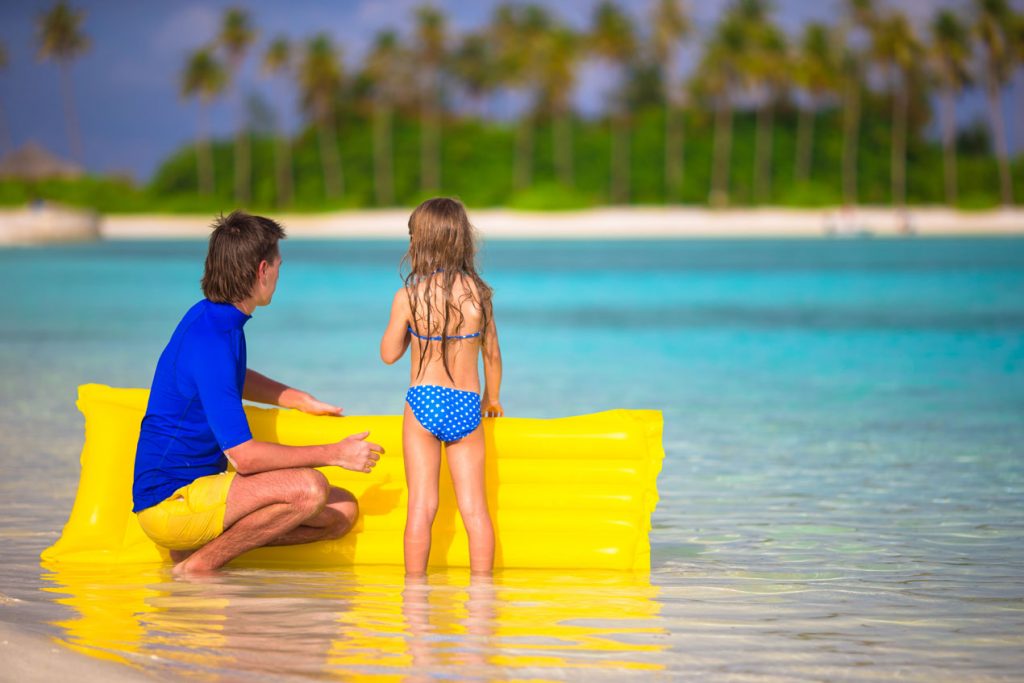 Little girl and young father with yellow float Caribbean Island beach vacation