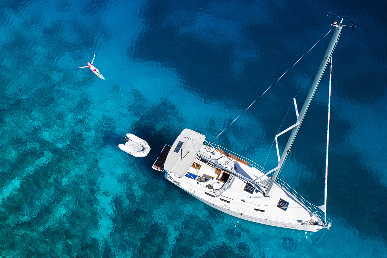 aerial view of sailing yacht, swimming woman and clear water in a Caribbean paradise