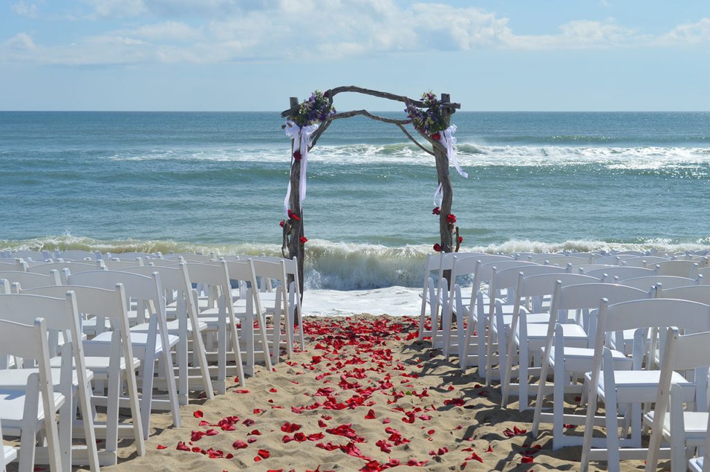 Martha's Vineyard oceanside beach wedding with arbor rose petals and white chairs