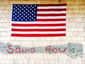 Squid Row Martha's Vineyard sign and American flag on shingled building Martha's Vineyard Nantucket getaways by land and sea