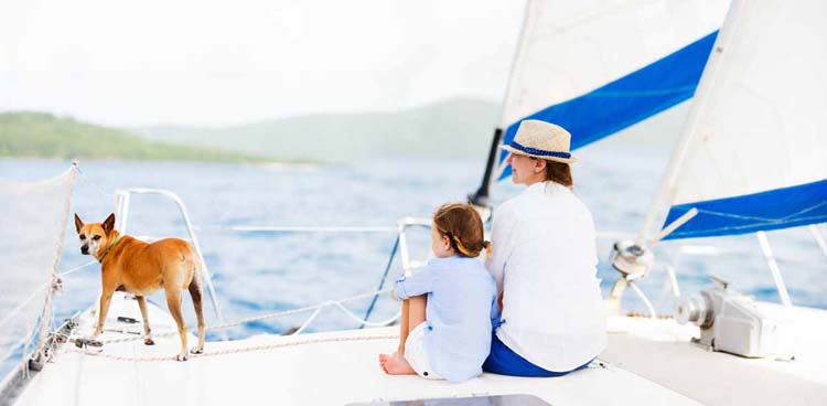 Back view of mother, daughter and their pet dog sailing on a luxury yacht or catamaran boat