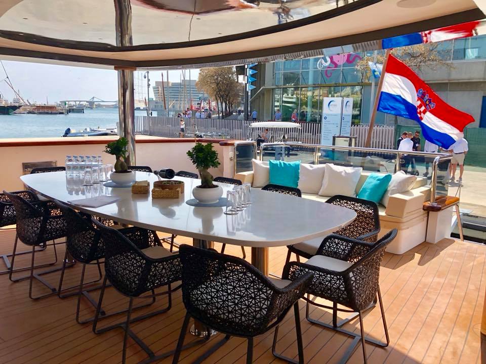 Covered al fresco dining area on the deck of the sailing yacht AIAXAIA with Croatian flag 2018 MYBA Charter Show