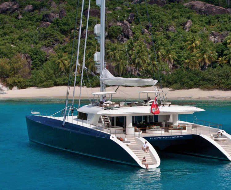 Yacht charterers sitting on the steps of the 145ft Pendennis sailing yacht catamaran HEMISPHERE off of Costa Rica. Operating in Central America, Australasia and other areas.