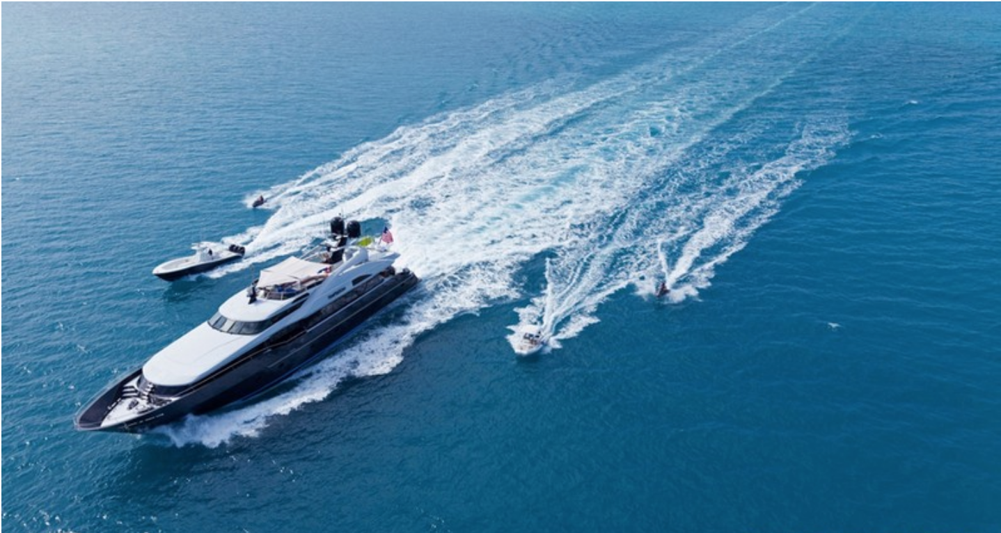 123ft motor yacht TEMPTATION traveling fast on the water, flanked by toys and tenders