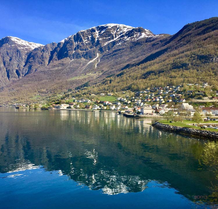 Town and snow-topped mountain reflected in water Norway
