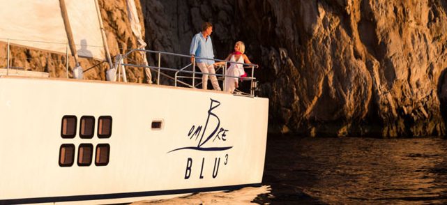 Couple enjoying Italian sun and Amalfi Coast cliffs on deck of 70ft luxury Sunreef catamaran S-Y Ombre Blu 3