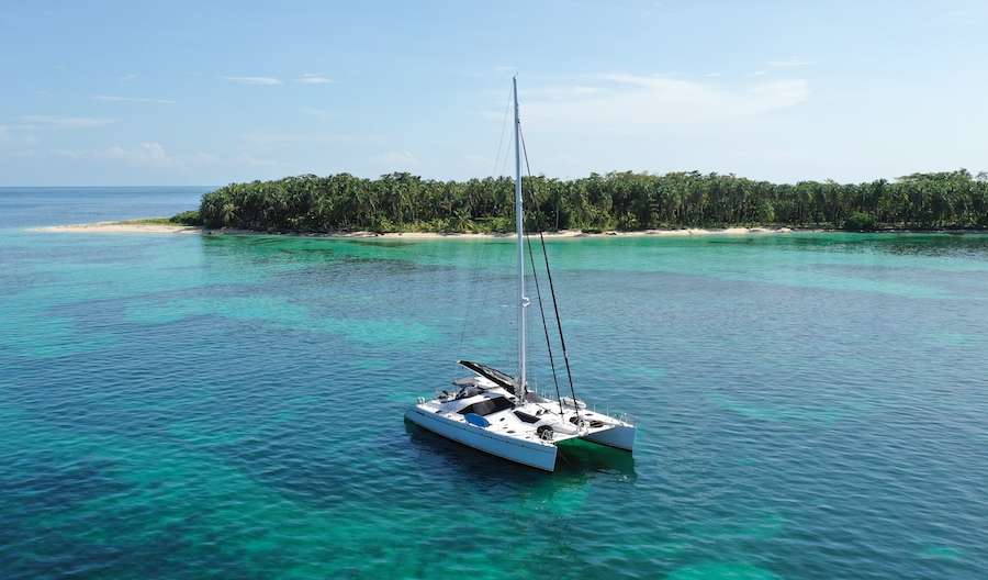 Sailing catamaran LOLALITA anchored off tiny island in the Caribbean
