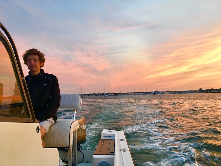 Captain Nick at the helm of the boat FamTrip at sunset on the Marblehead Harbor, Massachusetts