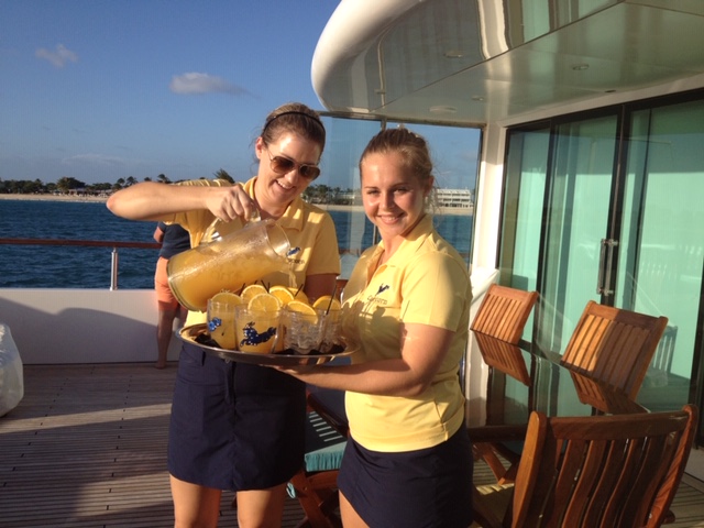 Charter yacht crew pouring iced orange drinks for passengers in St. Barths in the Caribbean