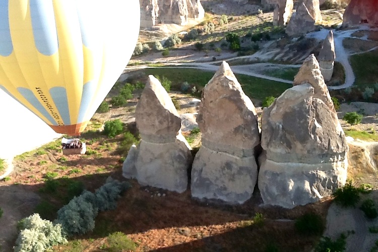 A hot air balloon approaches pointed rock formations in Cappadocia, Turkey