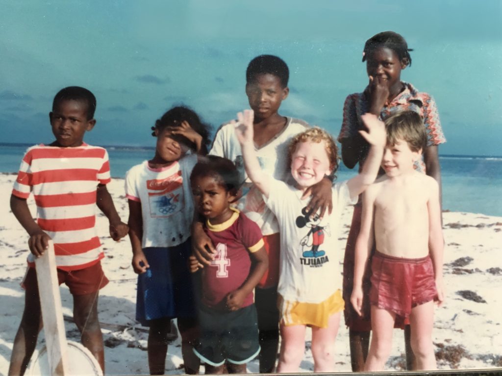Dangriga children with redheaded boy on Belize beach at Southwater Cay. Photo by C Kent. Yachting with youngsters and teens.