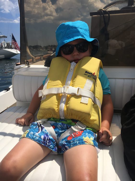 Young boy on yacht in life jacket, tuckered out from boating activities. Photo by Carol Kent.Yachting with youngsters and teens.