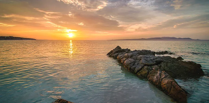 Sun setting into the Sea of Cortez near La Paz, Mexico orange sky and rocky island