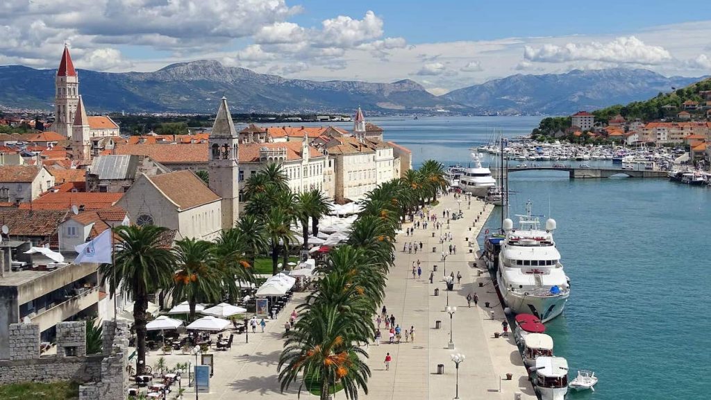 Trogir, Croatia esplanade with palm trees, buildings and boats