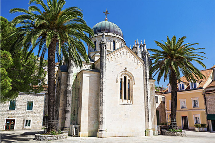 Church flanked by palm trees in Herceg Novi, Montenegro