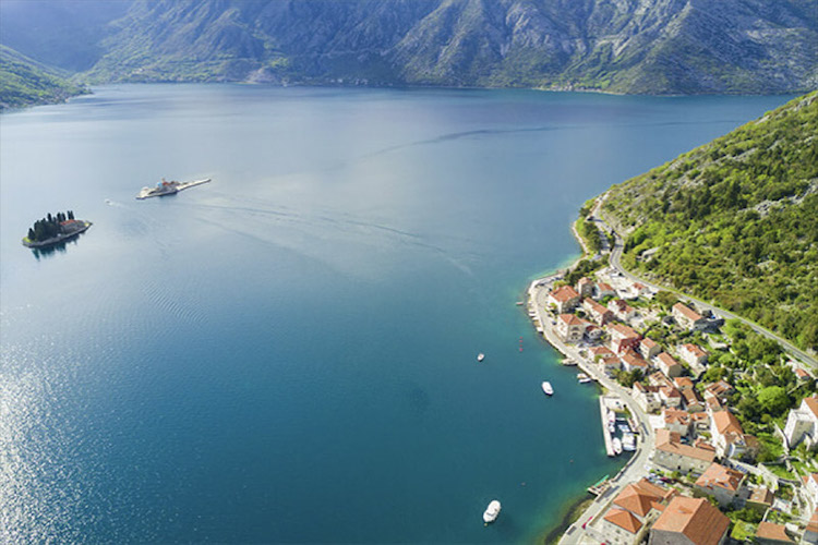 Aerial view of boat and island off Perast, Montenegro with mountains behind