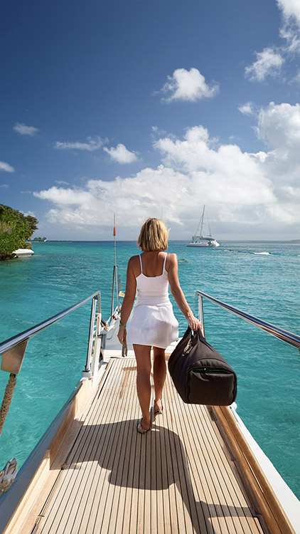 Woman carrying duffel bag as her luggage down ramp to yacht in the Caribbean